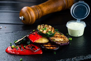 Grilled vegetables on dark stone background. Zucchini, bell peppers, tomatoes and eggplant
