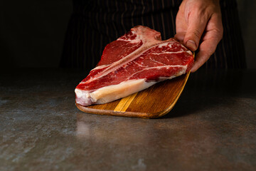 Raw T-bone steak cooking on stone table copy space