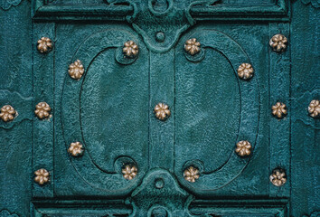 Old green metal door with pattern close-up. Vintage background. Medieval forging technologies.