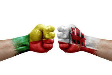 Two hands punch to each others on white background. Country flags painted fists, conflict crisis concept between benin and gibraltar