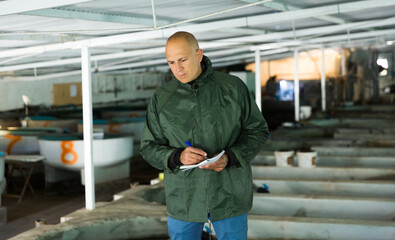 Fototapeta premium Portrait of man fish farm worker at trout breeding incubator