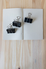three metal spring clips on a blank book on wood