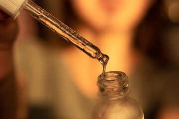 A young woman is using a hyaluronic acid hydrating serum.