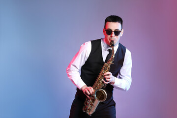 Young man in elegant outfit playing saxophone on color background. Space for text