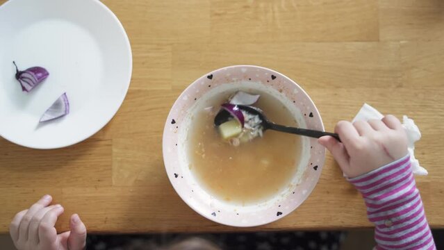 Close up of preschool girl portrait with eating soup at home. picky eater 