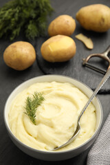 Freshly cooked homemade mashed potatoes and raw vegetables on dark grey table, closeup