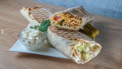 Shawarma chicken roll. Fresh roll of thin lavash or pita bread filled with grilled meat, cheese, carrots, sauce, green.