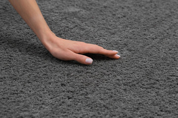 Woman touching soft grey carpet, closeup view