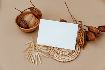 Minimal aesthetic background with blank card and dry floral branch on beige background. Wedding invitation template. Flat lay, top view, mock up, copy space ..