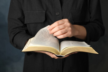 Humble woman reading Bible, closeup. Religious literature