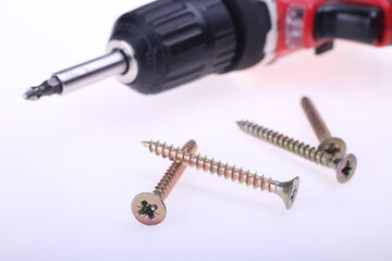 A battery powered screw gun drill next to a pile of screws on a white background text or copy space to the right, home improvement construction DIY remodel power tool concept, horizontal shot, closeup