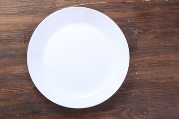 empty plate waiting for food, sitting on wooden table, top view, copy space. Hunger and lunch time concept