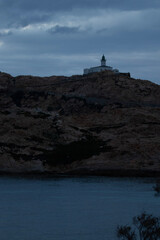 Fototapeta premium Phare en haut d'un rocher et de la mer, sous les nuages le soir