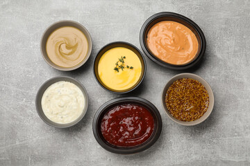 Many different sauces on grey table, flat lay