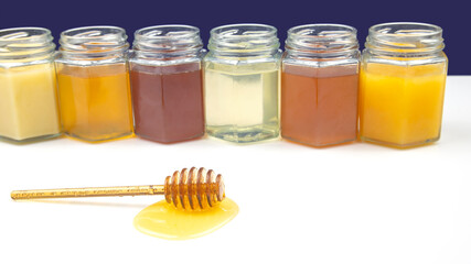 spoon with fresh honey and jars with different types of honey on a white background. organic vitamin food