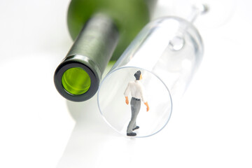 miniature people. alcohol addiction problem concept. an alcoholic stands on the edge of a glass...