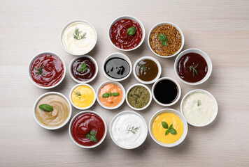 Many bowls with different sauces and herbs on wooden table