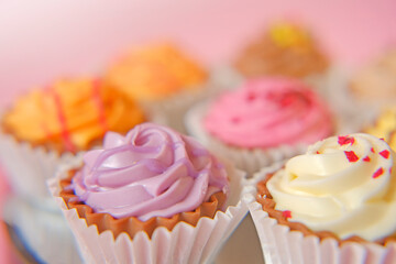 Cream cupcakes.cakes on a pink background. Assorted sweet table. Sweets and desserts. Baked goods and desserts