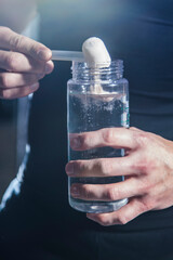 Pre Workout protein powder being poured into water bottle by athlete