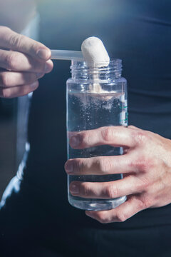 Pre Workout Protein Powder Being Poured Into Water Bottle By Athlete