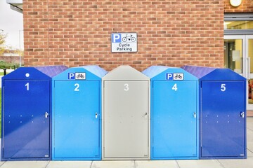 Row of Bicycle Lockers in front of a Brick Wall in a City Centre.