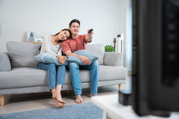 Obraz premium Asian young loving couple watch movie together in living room at home. 