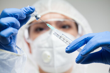 Female doctor or lab scientist holding syringe,filling injection with liquid vaccination dose
