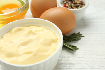 Delicious homemade mayonnaise with ingredients on white wooden table, closeup. Space for text