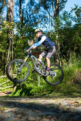 Fototapeta na wymiar Mountain biker jumping on his bike on a trail in the woods