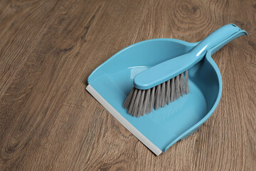 Plastic whisk broom with dustpan on wooden floor