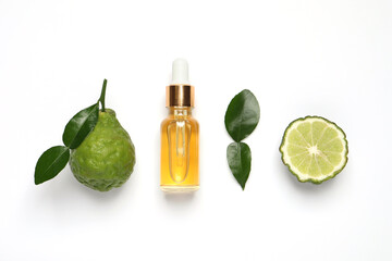 Glass bottle of bergamot essential oil and fresh fruits on white background, flat lay