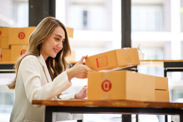 	
Startup SME small business entrepreneur SME or freelance Asian woman using a laptop with box, Young success Asian woman with her hand lift up, online marketing packaging box and delivery, SME concep