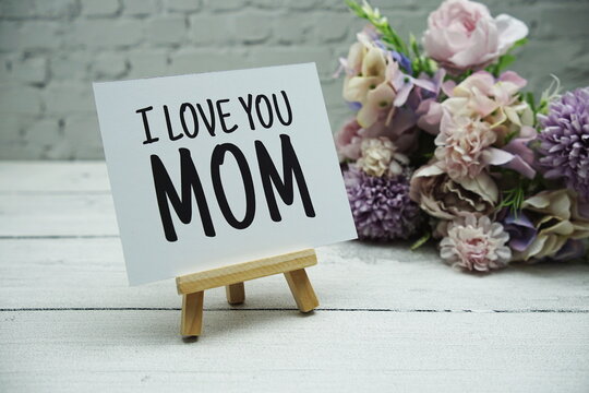 I Love You MOM text on white brick wall and wooden background