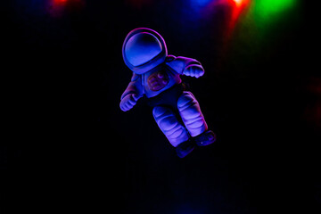Minimalistic shot of toys,A toy astronaut lies on a dark background. Space flights, toys for children made of plastic and polymer clay. Glare from the garland