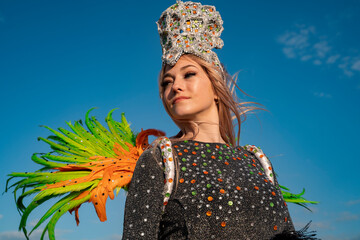 Closeup of blonde beautiful samba dancer with green and orange wings , with beautiful tiara on head