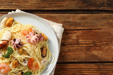Delicious spaghetti with seafood served on wooden table, top view. Space for text