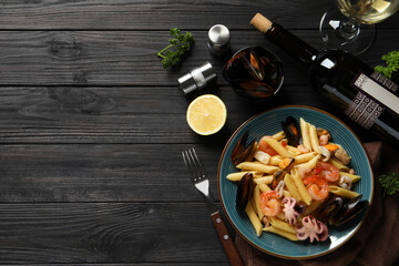 Delicious pasta with seafood served on black wooden table, flat lay. Space for text