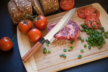 Solid Steel professional chef knife on wooden counter cutting board with freshly chopped fruits, vegetables, meet, and bread
