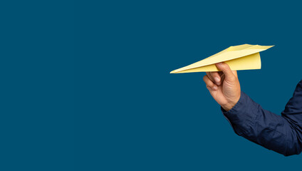 Hand holding a yellow rocket paper on a blue background. Business startup concept