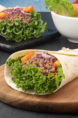 Wrap sandwich of lettuce, minced beef, carrot and onion.