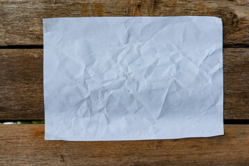 CRUSHED WHITE PAPER IN TEXTURE AND RUSTIC WOODEN BACKGROUND