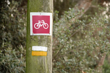 White and yellow Marked on a small PR trail log next to a sign indicating a bicycle route.