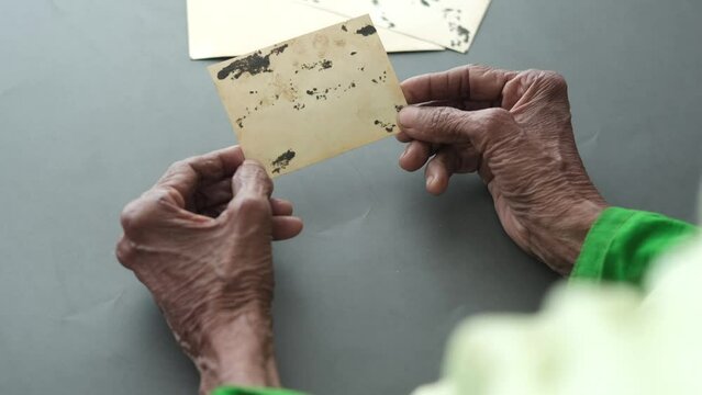 senior women holding f Old photos bunch on black 