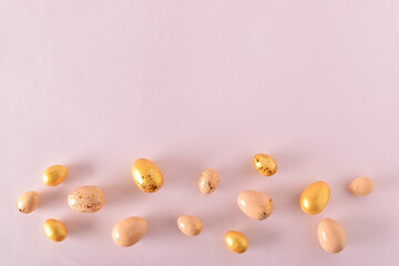 Various Easter eggs of yellow shades lie on a pink background. Easter background with painted eggs and sequins. Copy space. Flat lay, top view.