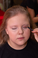 A makeup artist makes makeup for a child.