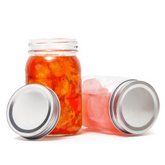 Glass mason jars with red and pink juice liquid drinks on white background