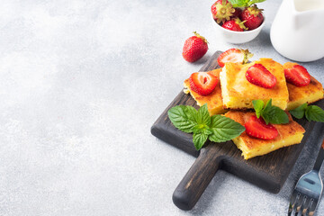 Cottage cheese casserole with strawberries and mint. Delicious homemade dessert made of curd and fresh berries with cream. Gray concrete background, copy space.