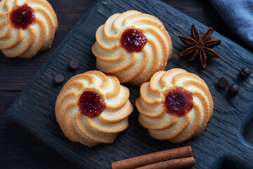 Kurabye shortbread cookies with berry jam in a black plate. Delicious dessert, dark wooden background.