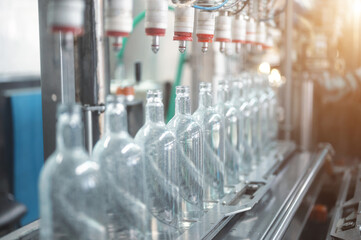 Filling glass bottles with vodka drink on production line