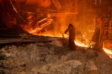 The process of releasing pig iron from a blast furnace. A man works with molten metal